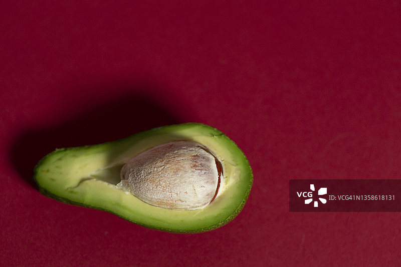 红色背景下的牛油果切片特写图片素材