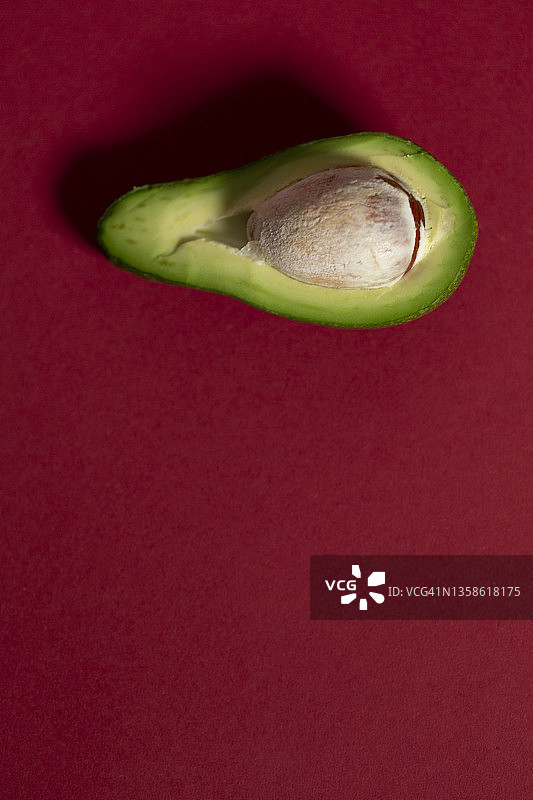 红色背景下的牛油果切片特写图片素材