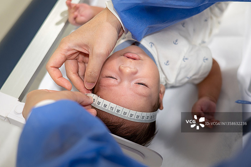 在医院的例行新生儿检查中，医生测量新生儿的身体图片素材