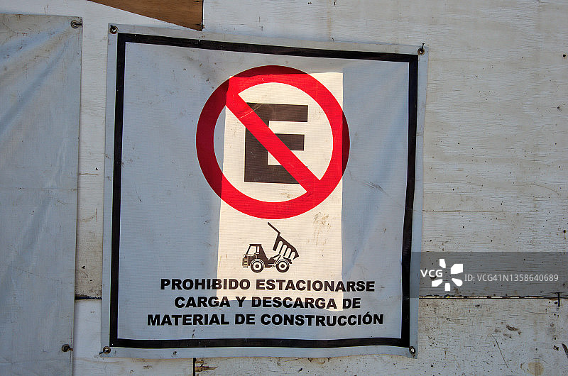 西班牙语警告标志，在建筑工地围栏上写着“禁止停车。装卸建筑材料”图片素材