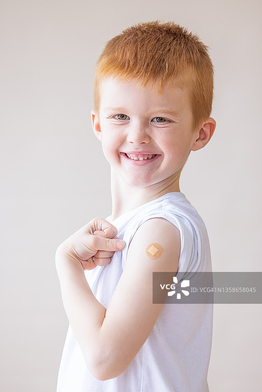 为接种新冠疫苗感到自豪的可爱男孩图片素材