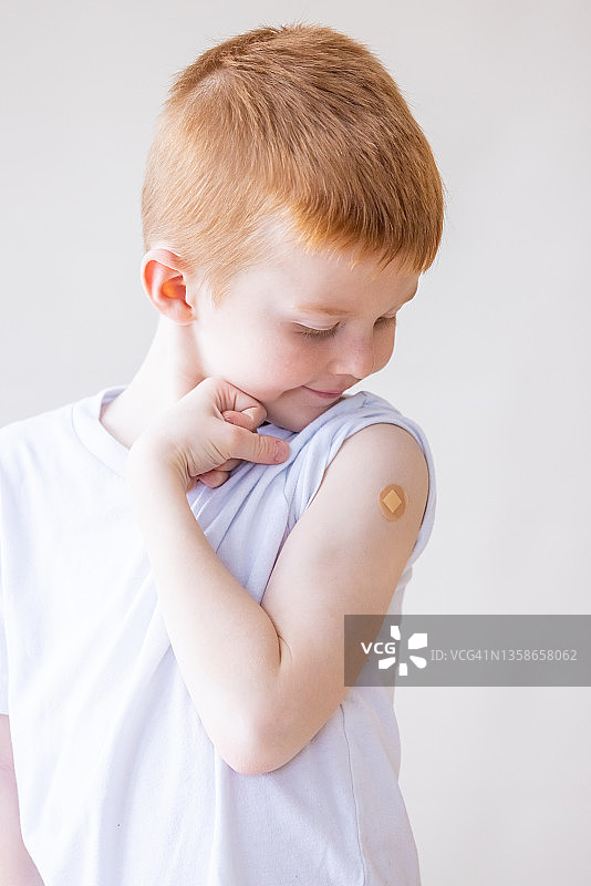 为接种新冠疫苗感到自豪的可爱男孩图片素材