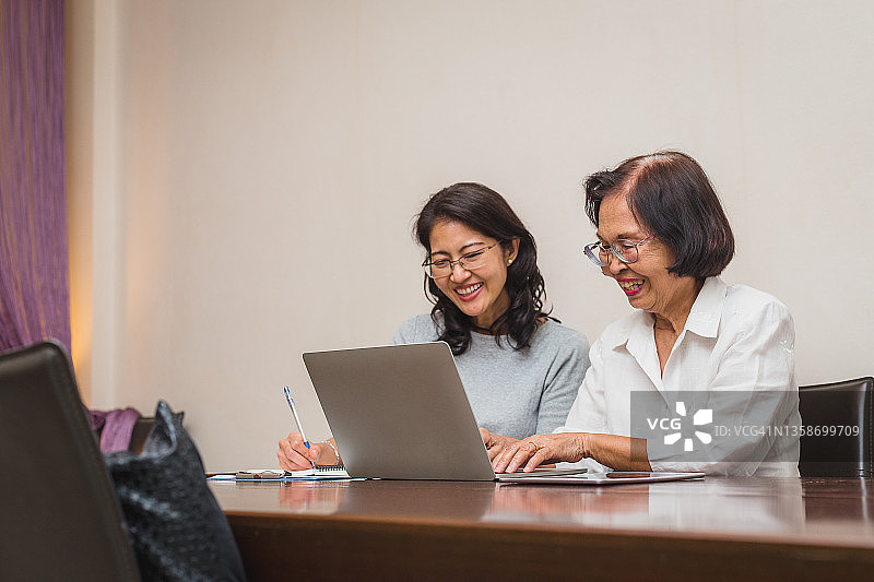 亚洲女儿和年长母亲在家中一起使用笔记本电脑工作图片素材