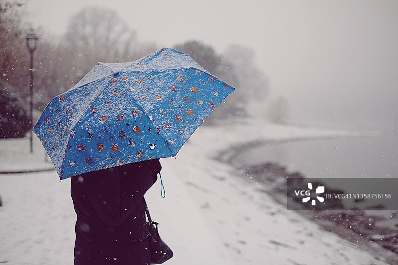 冬夜，灯光下，女孩打着伞在雪中慢跑图片素材