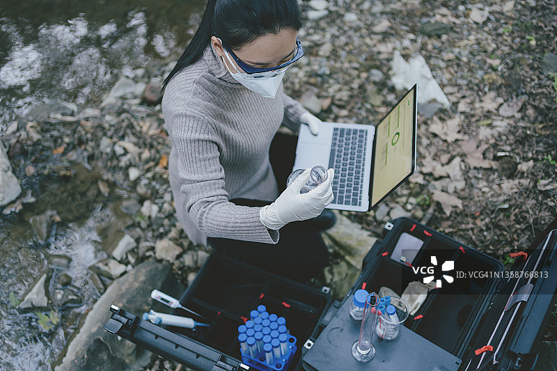 亚洲女科学家使用笔记本电脑测量山河水质图片素材