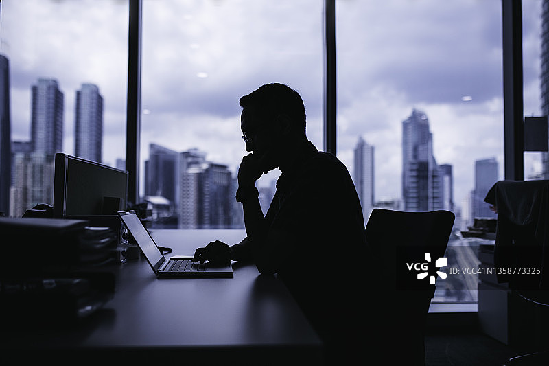 在办公室用笔记本电脑工作的英俊年轻商人图片素材