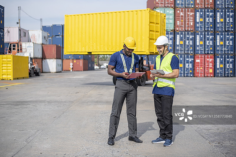 两位工程师集装箱货物工头戴着头盔，站着使用对讲机检查库存装入集装箱的专业人员。物流和商业出口图片素材