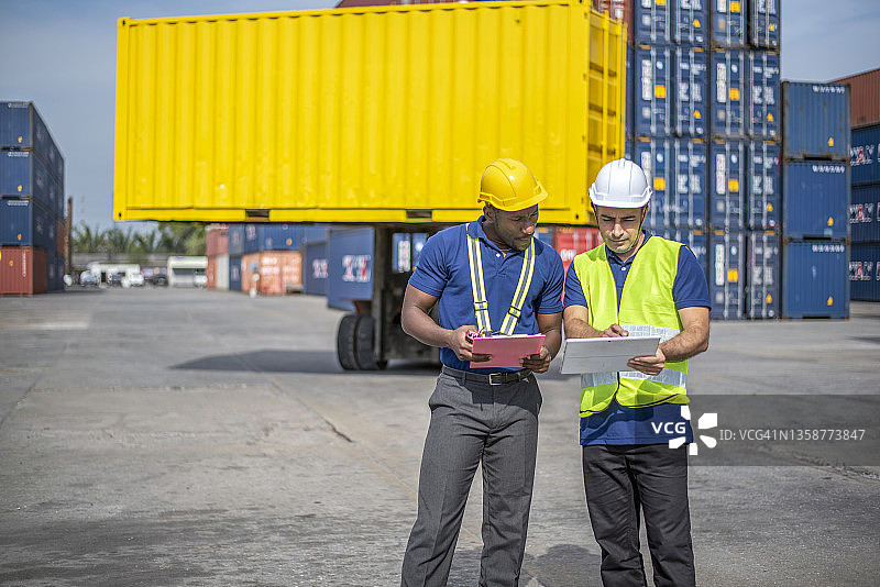 两位工程师集装箱货物工头戴着头盔，站着使用对讲机检查库存装入集装箱的专业人员。物流和商业出口图片素材