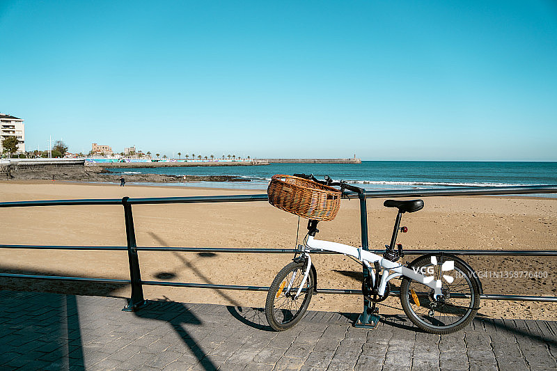 停在海滩上的自行车，可俯瞰大海和防波堤灯塔图片素材