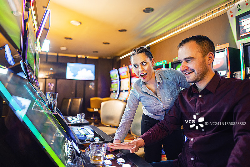两名朋友在赌场玩老虎机图片素材