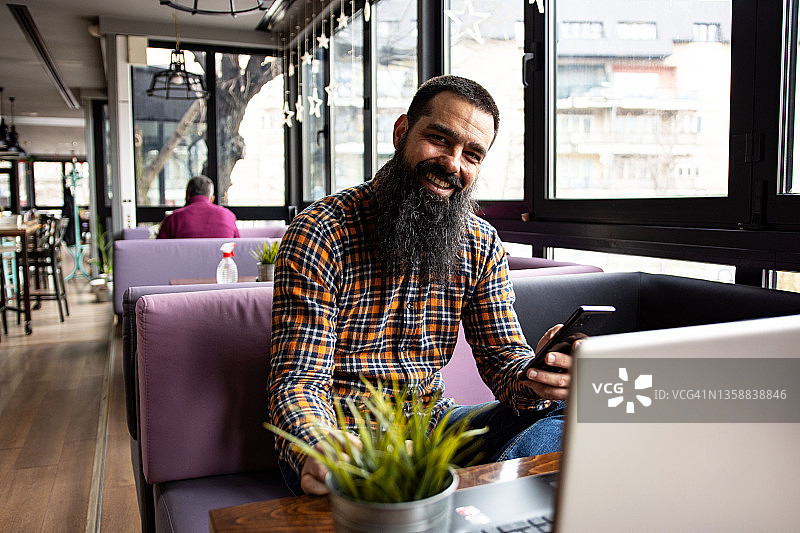 男自由职业者在咖啡馆休息时用智能手机发送消息的肖像图片素材