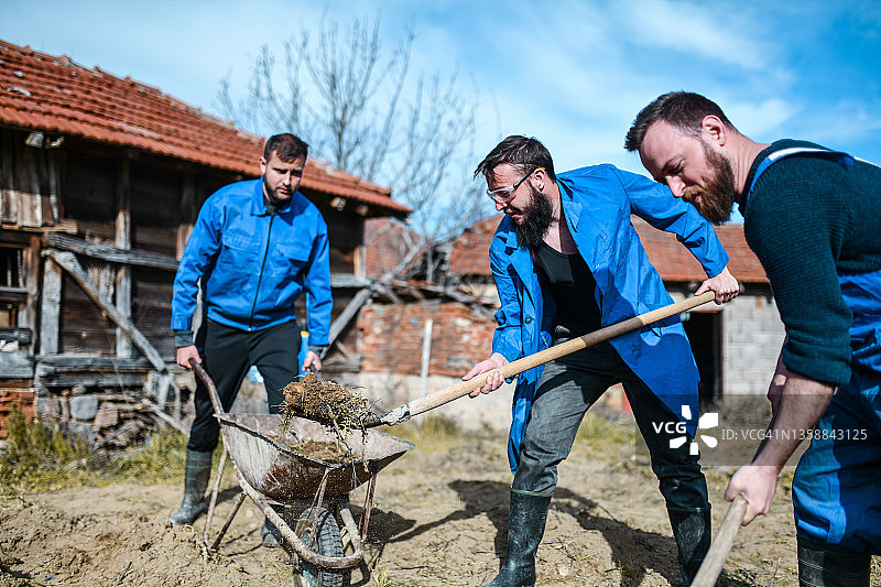 农场工人辛勤劳作，用手推车装满泥土图片素材