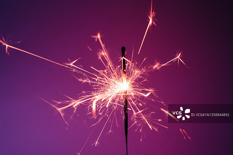 粉色背景上闪耀着美丽火花的燃烧烟花棒。新年或生日庆祝概念。展示2022年度代表色图片素材