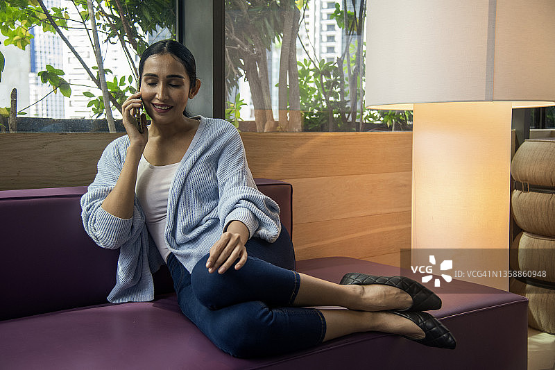 印度裔妇女在沙发上休息时打电话图片素材