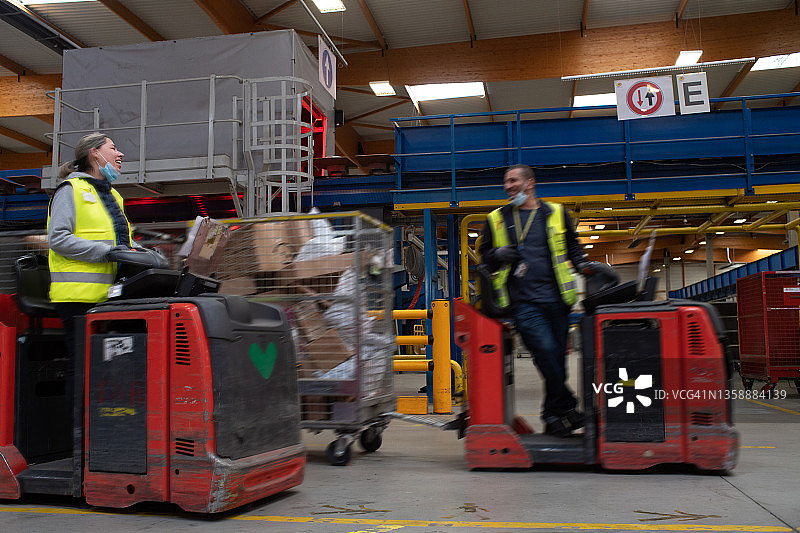 两位电动拖拉机司机在工业场所工作时开玩笑图片素材