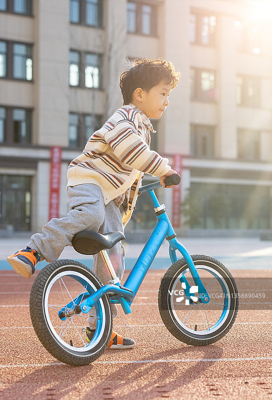 在学校操场骑自行车的小男孩图片素材