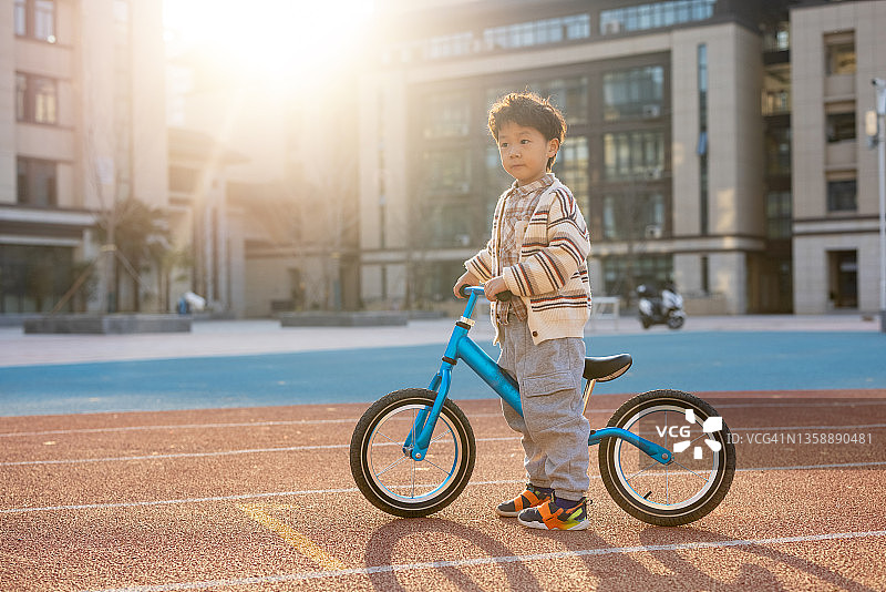 在学校操场骑自行车的小男孩图片素材