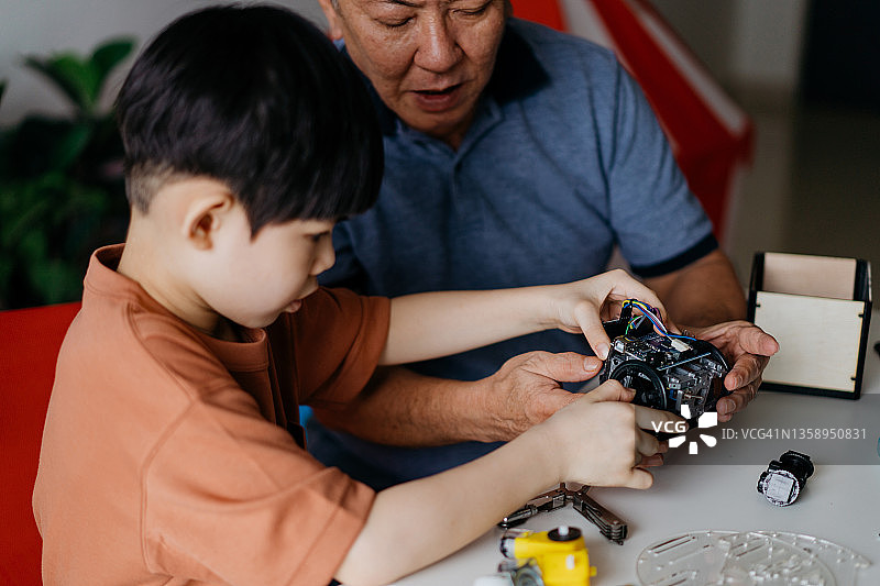 爷爷和孙子在家组装机器人玩具图片素材