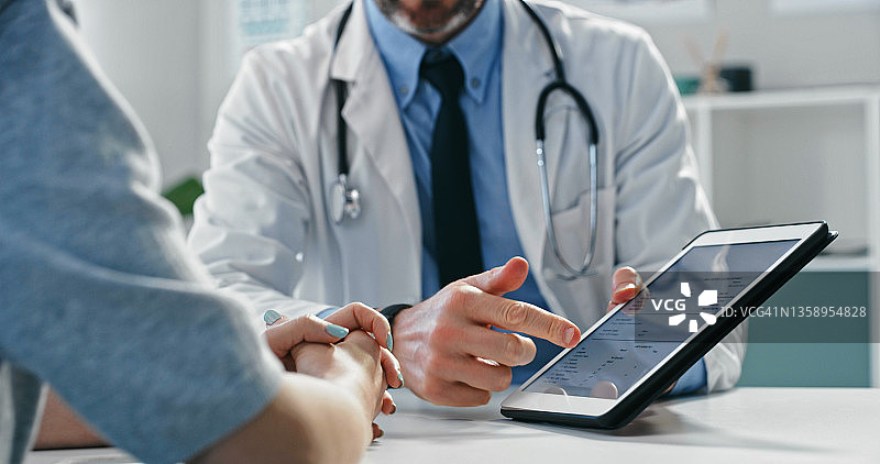 医生与患者坐在一起并在平板电脑上向她展示测试结果的局部照片图片素材