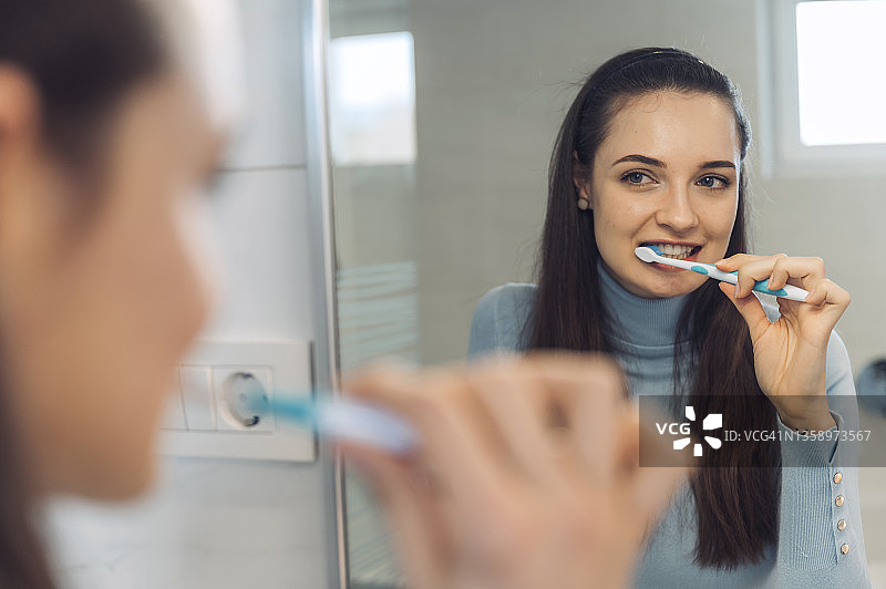 美丽的白人女孩在镜子前刷牙图片素材