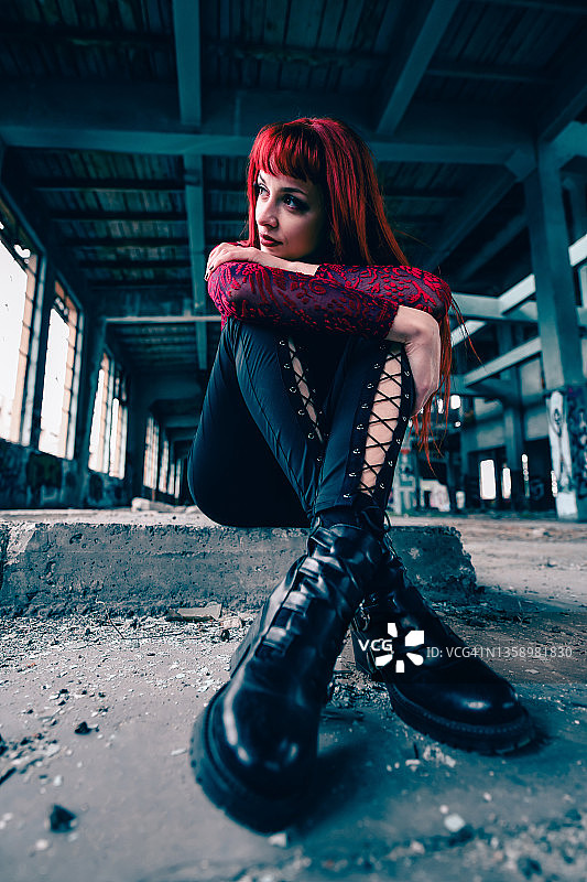 坐在废弃工厂废墟台阶上的哥特式红发女人图片素材