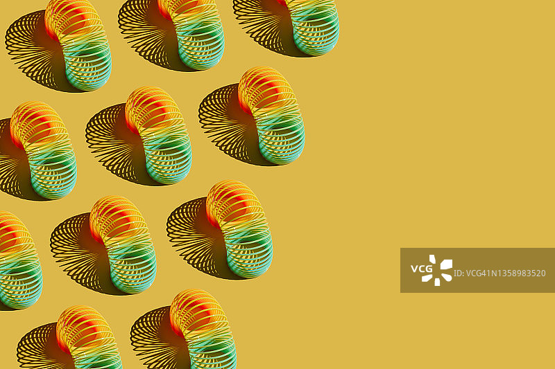 黄色背景上的彩虹螺旋弹簧玩具图案图片素材