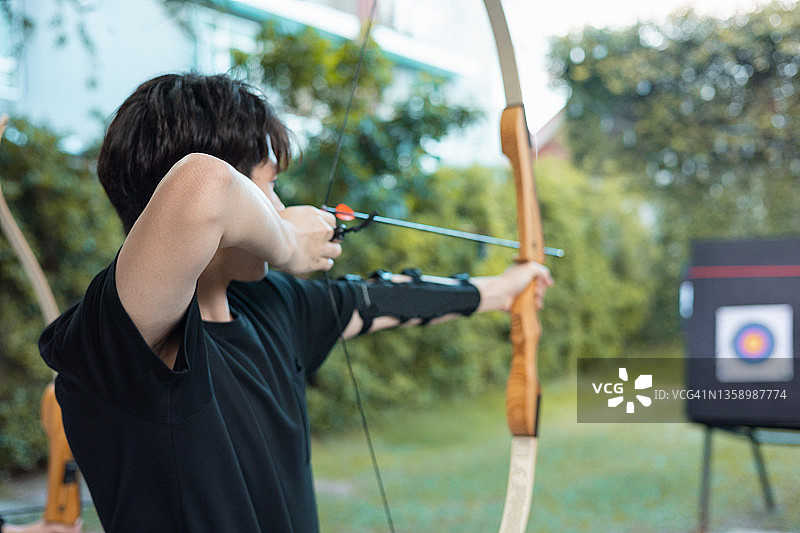 夕阳下运动场上射箭的运动员背影图片素材