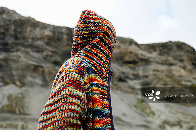 身穿彩色针织毛衣站在山景背景下的不明身份者图片素材