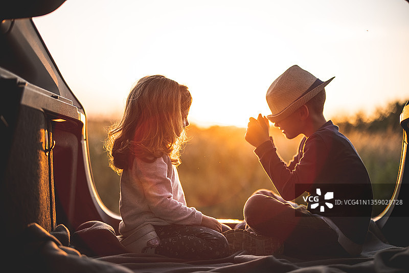 快乐的孩子们坐在汽车后备箱里玩耍图片素材