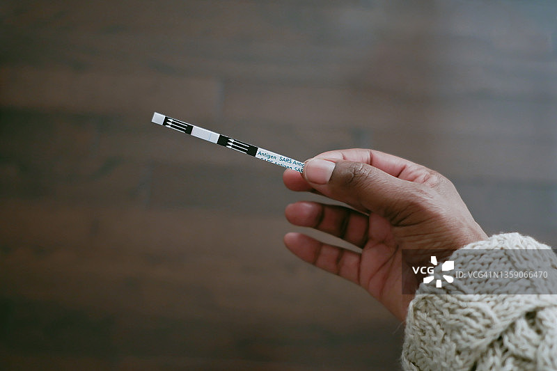 女人拿着显示阴性结果的COVID-19测试条图片素材