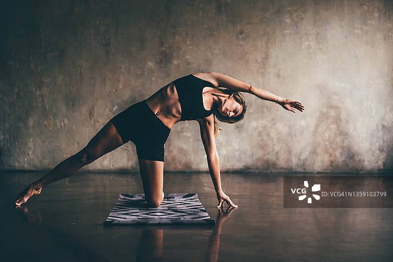 穿着黑色运动服的年轻女教练练习瑜伽图片素材