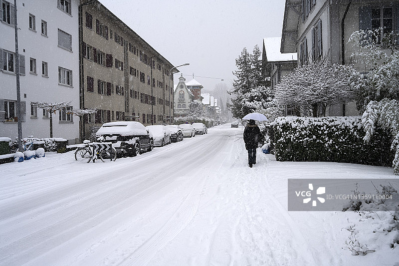 在尼道下雪的街道上，男人撑着伞走路图片素材