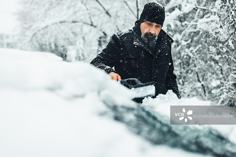 暴风雪后清洁汽车的中年男人图片素材