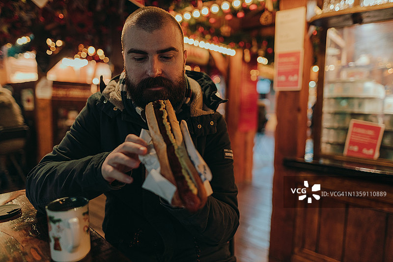 在圣诞市场享用香肠的微笑男人图片素材