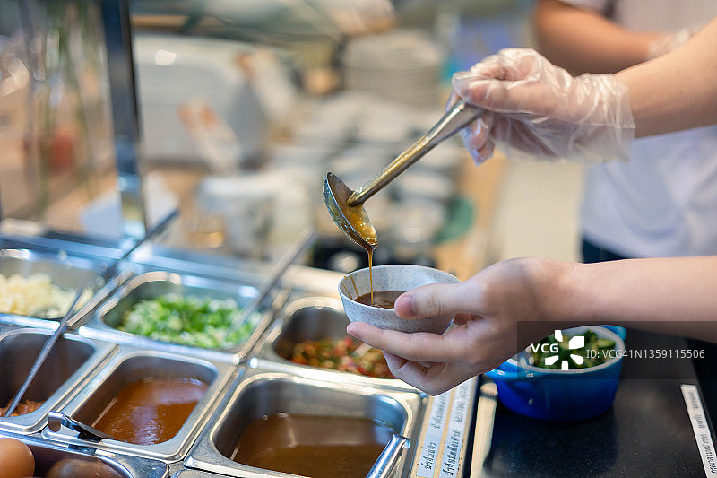 从日式自助寿喜锅中取酱汁的手部局部图像图片素材