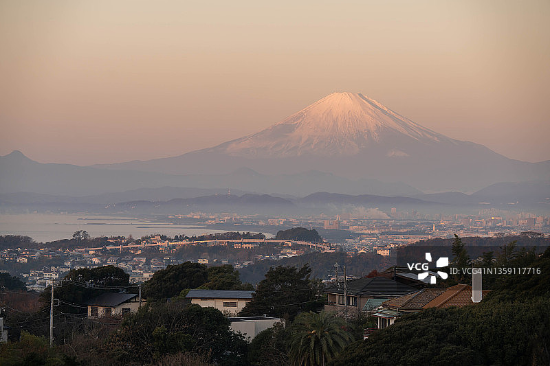 日本神奈川县的富士山雪景与海边居民区图片素材