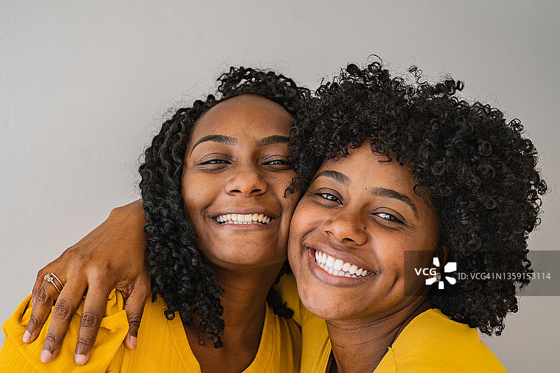 身穿黄色衣服的微笑姐妹的肖像图片素材