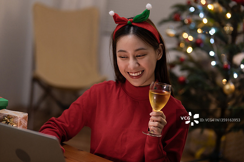 在家进行在线圣诞庆祝活动的年轻有魅力的亚洲女性图片素材