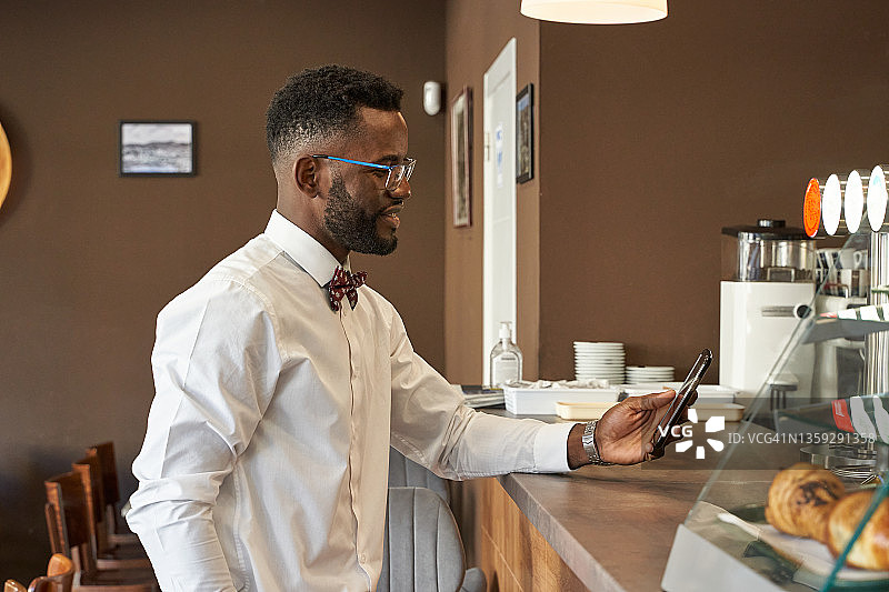 一位非洲自由职业者在咖啡馆或酒吧柜台打电话的肖像图片素材