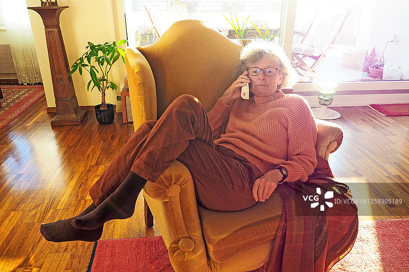 坐在扶手椅上打电话的年长女人图片素材