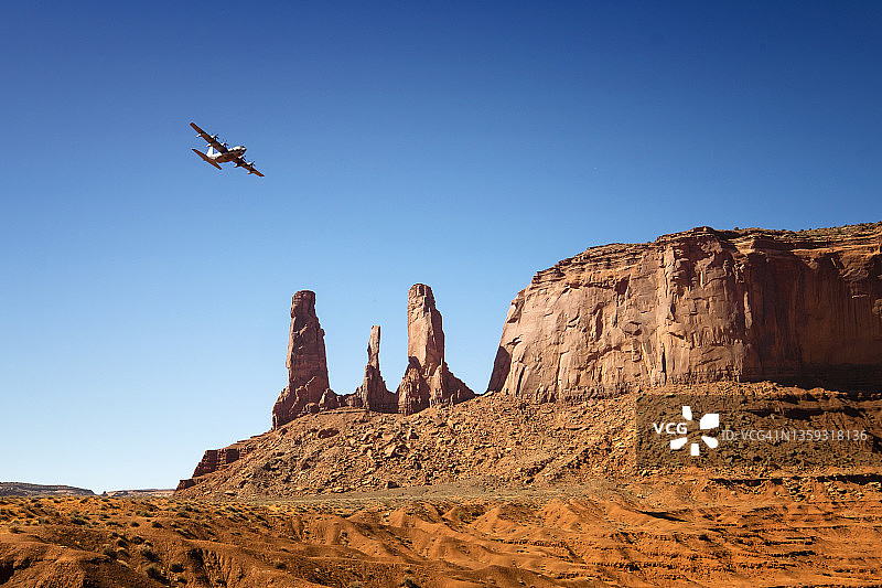 飞机飞越亚利桑那州纪念碑谷的三姐妹砂岩孤峰图片素材
