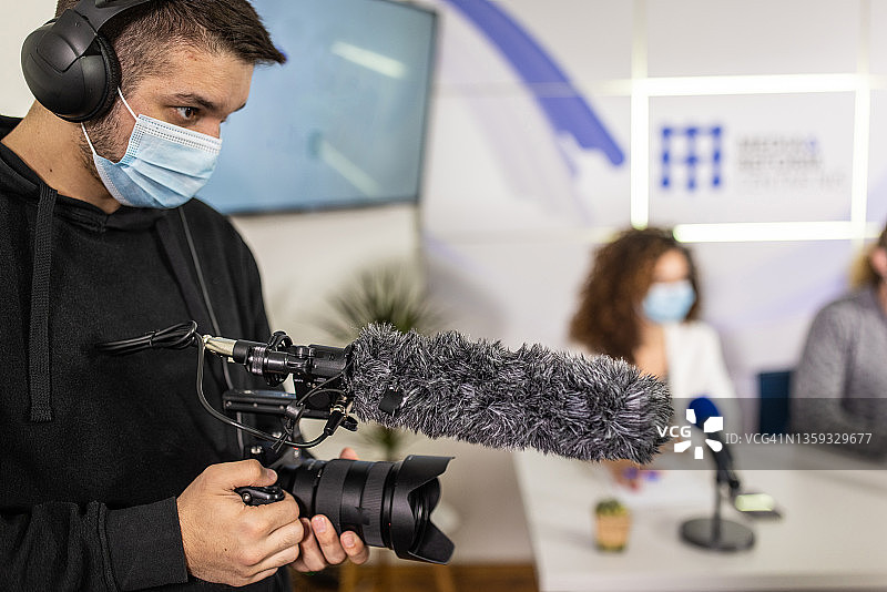 摄影师在媒体中心拍摄新闻发布会，佩戴防护口罩图片素材