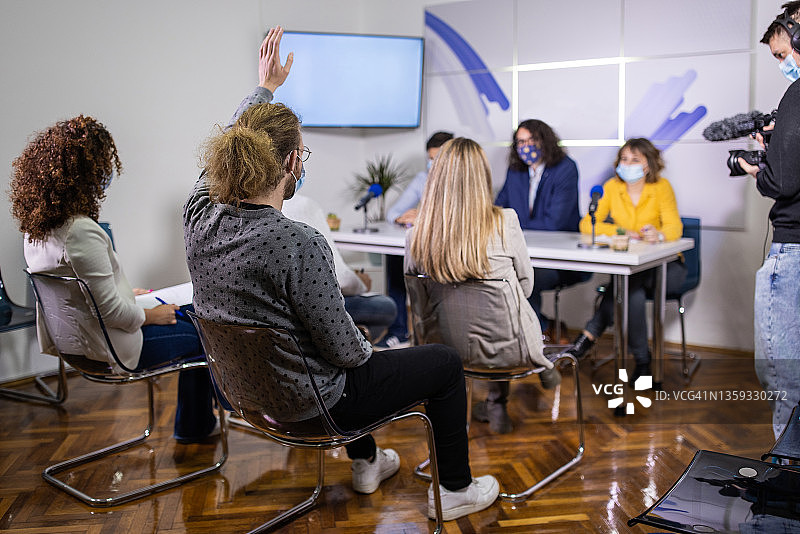 男记者在新闻发布会上举手提问图片素材