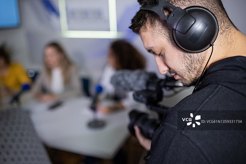 媒体中心内，拍摄新闻发布会的白人摄影师特写图片素材