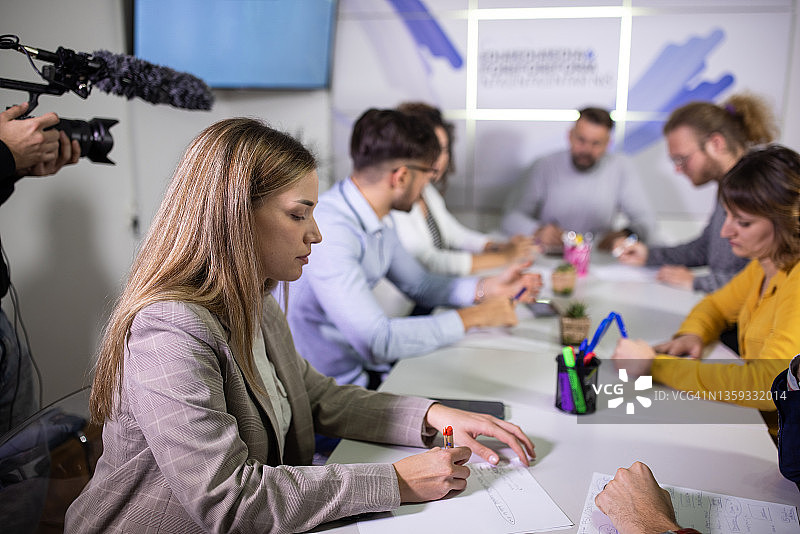 在媒体中心拍摄新闻发布会的白人摄像师图片素材