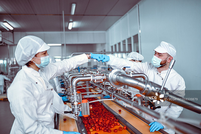 男同事和女同事在胡椒粉灌装生产线上互相击拳鼓励图片素材