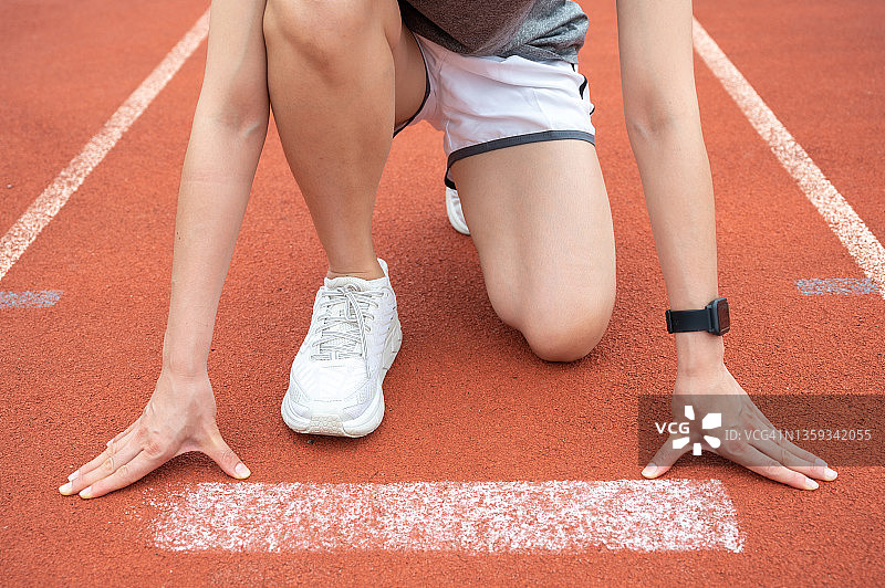 女运动员在体育场跑道上准备短跑起跑姿势的裁剪照片图片素材
