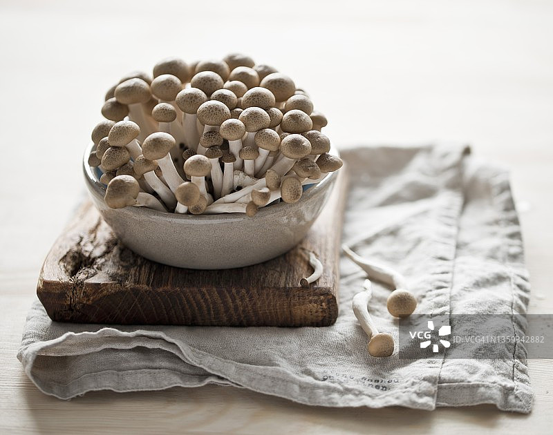 砧板上陶瓷碗里的新鲜真姬菇图片素材