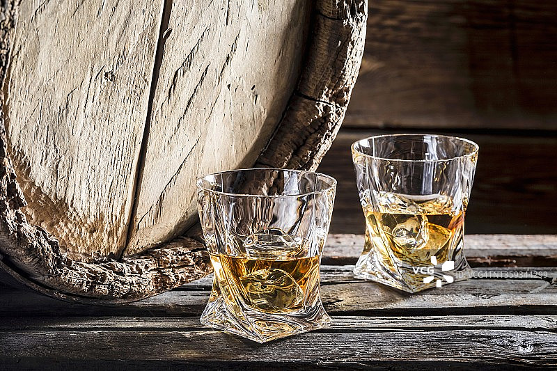 两杯加冰威士忌，背景是旧木桶图片素材