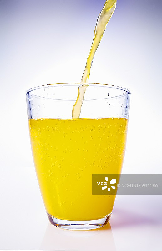 橙汁倒入高脚玻璃杯中图片素材